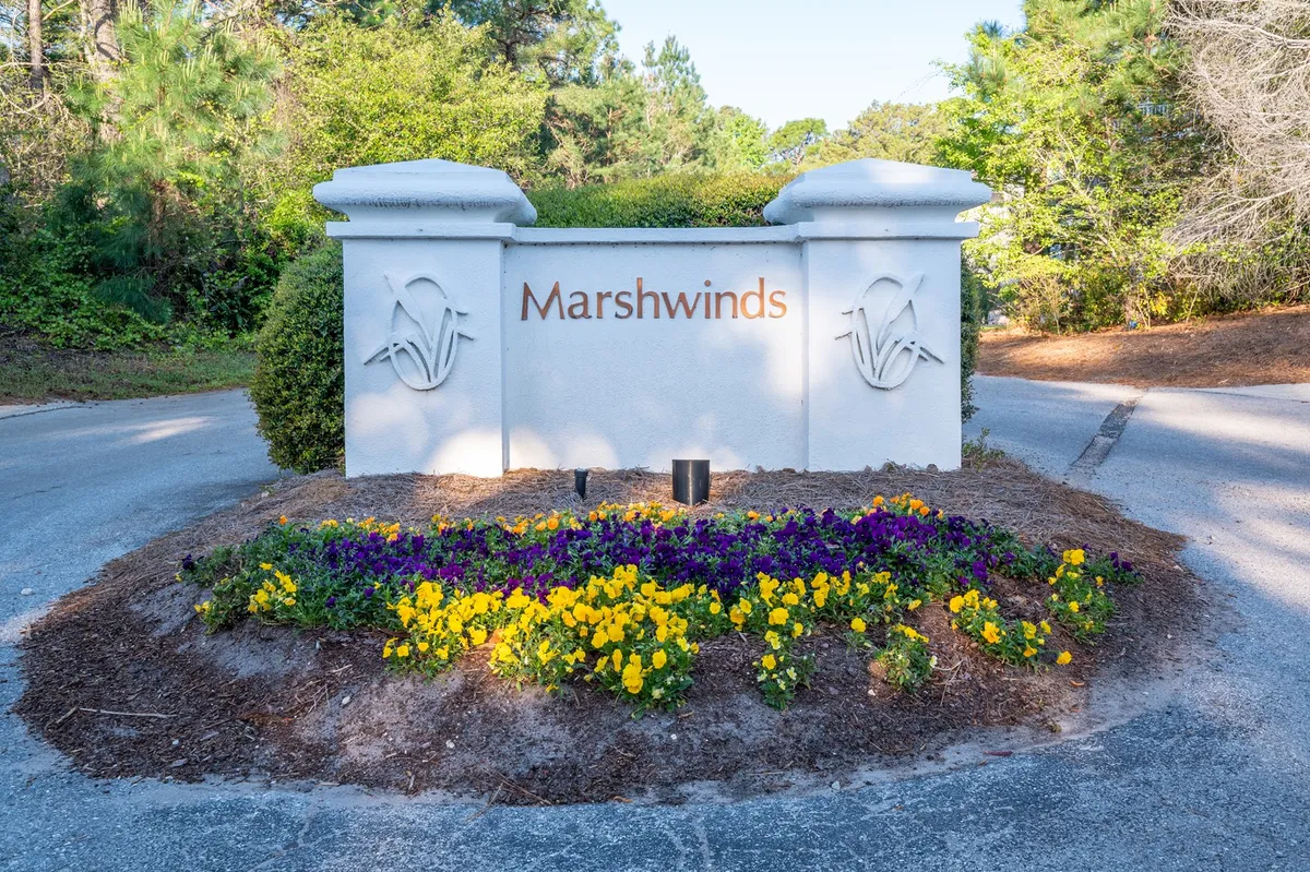 The entrance to the Marshwinds community, marked by a welcoming sign, vibrant flower beds, and lush surrounding greenery. The inviting setting creates a positive first impression and hints at the neighborhood’s charm.