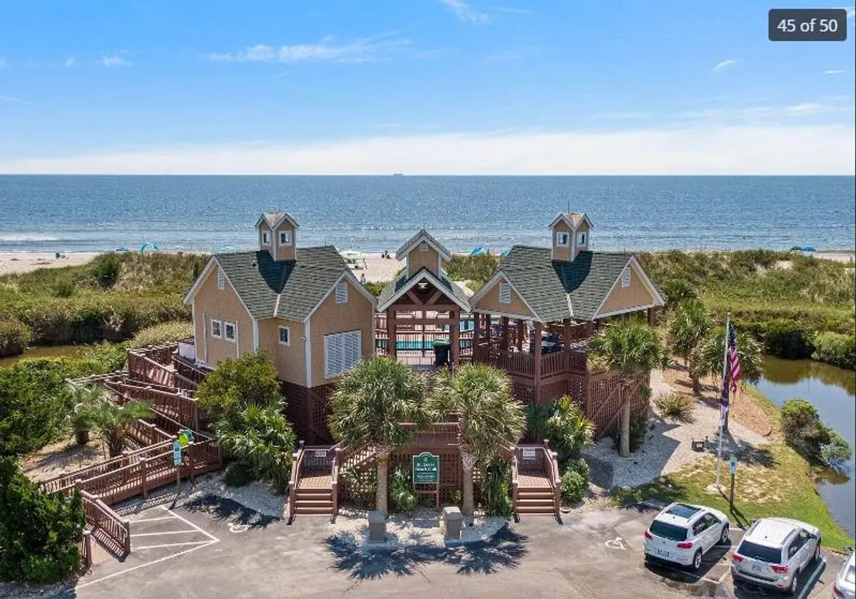 This image captures a beachfront property with a boardwalk leading to the sand, framed by palm trees and offering a direct waterfront view. The setting is perfect for beach activities, family gatherings, and outdoor events, all under a relaxed and cheerful mood.
